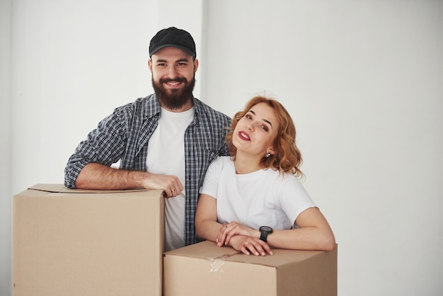 Apoiado em caixas. Casal feliz juntos em sua nova casa. Concepção de movimento