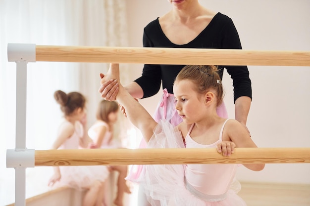 Foto apoiando-se no suporte de madeira pequenas bailarinas se preparando para o desempenho