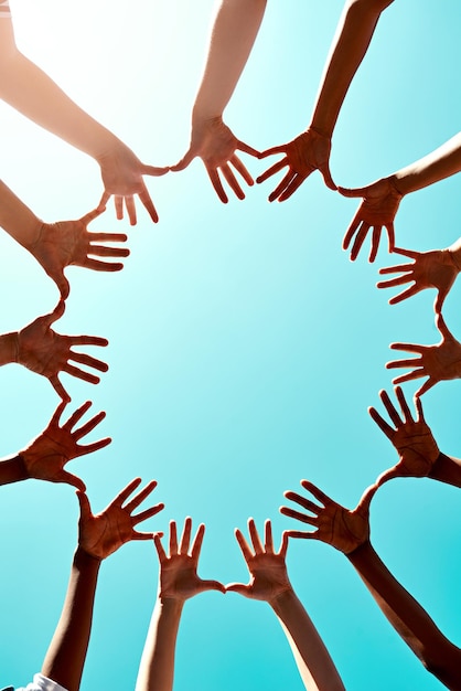 Foto apoio comunitário com as mãos no ar e no céu azul ao ar livre para unidade diversidade ou colaboração luz do sol e grupo de pessoas com a mão em um círculo para solidariedade ou confiança com reflexo de lente