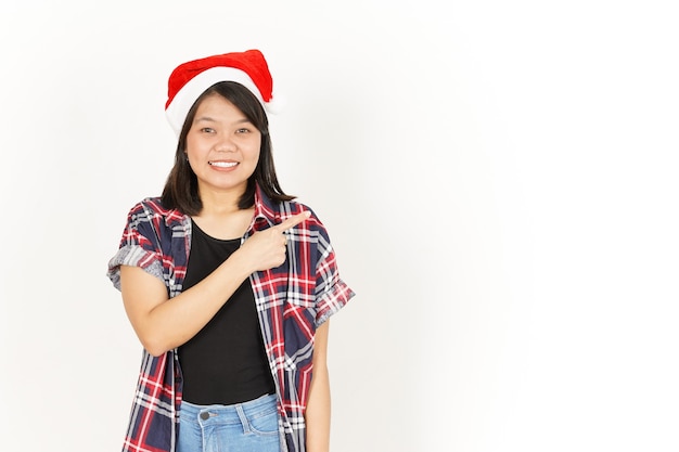 Apontando e apresentando à parte da bela mulher asiática vestindo camisa xadrez vermelha e chapéu de Papai Noel