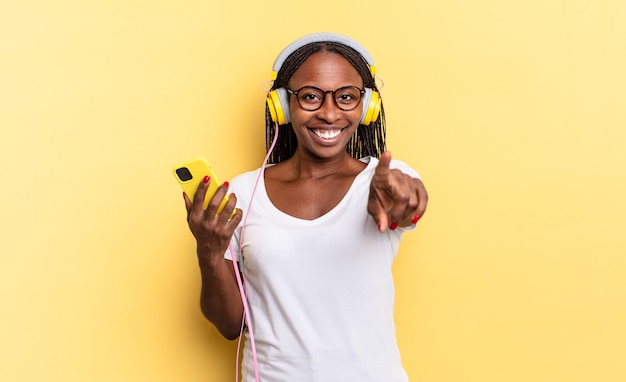 apontando para a câmera com um sorriso satisfeito, confiante e amigável, escolhendo você e ouvindo música