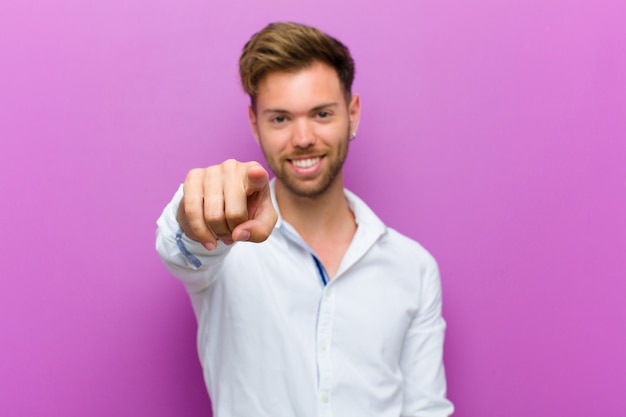 apontando para a câmera com um sorriso satisfeito, confiante e amigável, escolhendo você