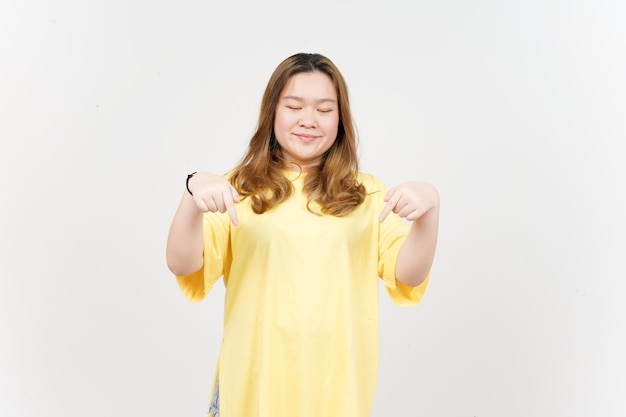 Apontando para baixo e mostrando o espaço em branco da bela mulher asiática vestindo camiseta amarela