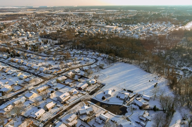 Após a queda de neve em uma pequena cidade residencial com telhados cobertos de neve, vista aérea do inverno no campo dos EUA