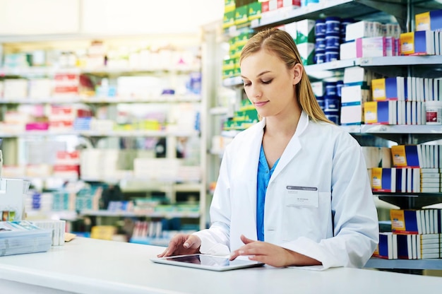 Apotheke Frau oder Apothekerin mit digitalem Tablet, um Medikamente zu bestellen, Inventar zu überprüfen und zu inspizieren Gesundheitsexpertin und Technologie für Forschungsinformationen Pillen und Rezepte