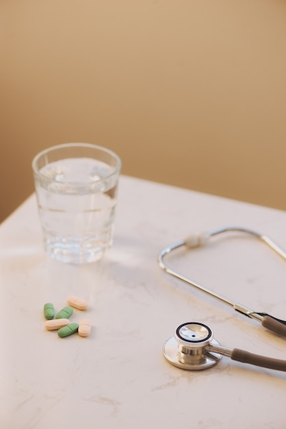 Apothekenhintergrund auf einem weißen Tisch. Tabletten auf weißem Hintergrund. Tabletten. Medizin und gesund. Nahaufnahme von Kapseln. Stethoskop auf weißem Hintergrund aus Holz.