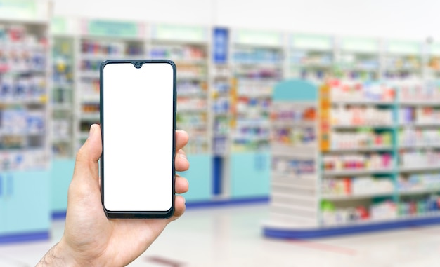 Apothekenhintergrund verwischen Zähler der Apotheke mit Medikamententabletten Pillen und Hand mit Smartphone ...