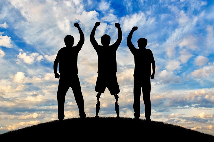 Foto apoyar y ayudar a las personas con discapacidad el concepto. feliz hombre discapacitado con una pierna protésica de pie y sus amigos al atardecer en la cima de la colina