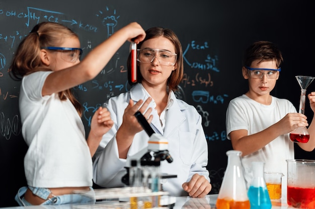 Apoyo del maestro al experimento del estudiante líquido en tubo en el laboratorio Erudición