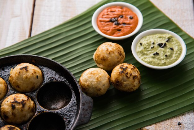 Appam o Mixed dal o Rava Appe servido sobre un fondo de mal humor con chutney verde y rojo. Receta de desayuno popular del sur de la India en forma de bola. Enfoque selectivo