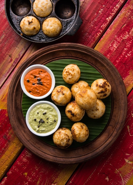 Appam o Mixed dal o Rava Appe servido sobre un fondo de mal humor con chutney verde y rojo. Receta de desayuno popular del sur de la India en forma de bola. Enfoque selectivo