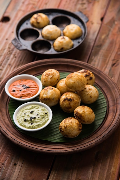 Appam o Mixed dal o Rava Appe servido sobre un fondo de mal humor con chutney verde y rojo. Receta de desayuno popular del sur de la India en forma de bola. Enfoque selectivo