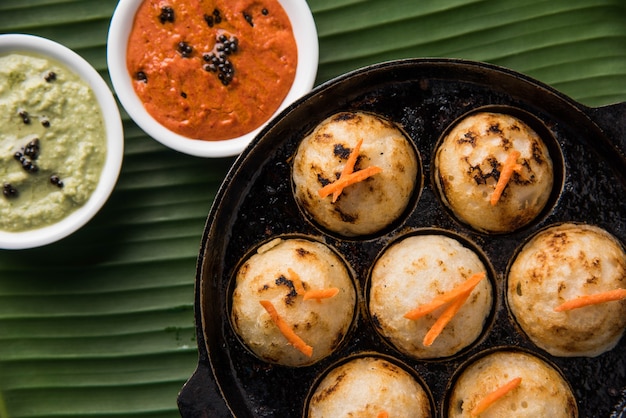 Foto appam o mixed dal o rava appe servido sobre un fondo de mal humor con chutney verde y rojo. receta de desayuno popular del sur de la india en forma de bola. enfoque selectivo