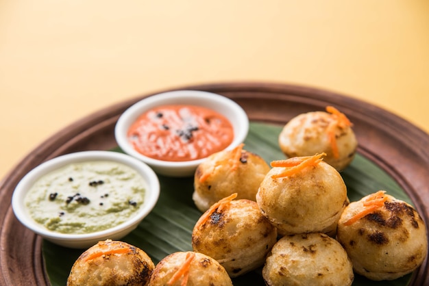 Appam o Mixed dal o Rava Appe servido sobre un fondo de mal humor con chutney verde y rojo. Receta de desayuno popular del sur de la India en forma de bola. Enfoque selectivo