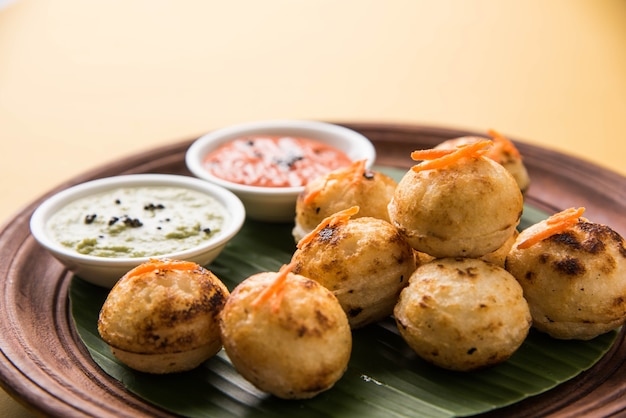 Appam o Mixed dal o Rava Appe servido sobre un fondo de mal humor con chutney verde y rojo. Receta de desayuno popular del sur de la India en forma de bola. Enfoque selectivo