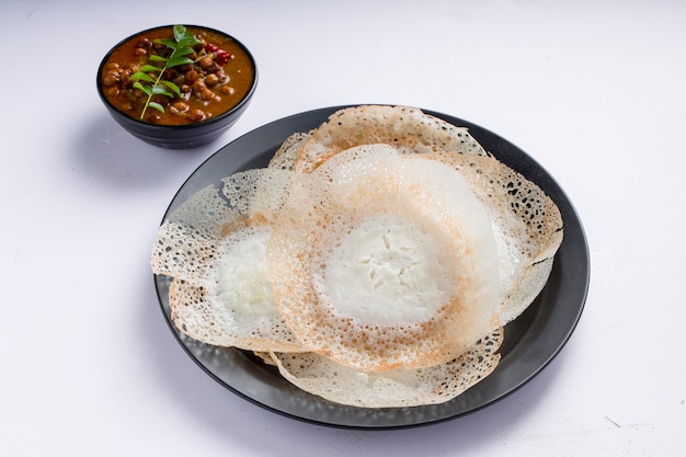 Appam o velliappam o kallappam o paalappam, sabroso y delicioso desayuno en el sur de la india y con una buena combinación de kadala curry o bengala gram curry, colocado sobre un fondo blanco.