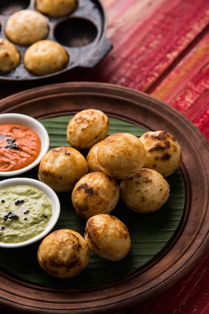 Appam oder Mixed Dal oder Rava Appe serviert auf stimmungsvollem Hintergrund mit grünem und rotem Chutney. Ein beliebtes südindisches Frühstücksrezept in Kugelform. Selektiver Fokus