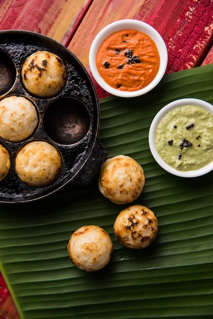 Appam oder Mixed Dal oder Rava Appe serviert auf stimmungsvollem Hintergrund mit grünem und rotem Chutney. Ein beliebtes südindisches Frühstücksrezept in Kugelform. Selektiver Fokus
