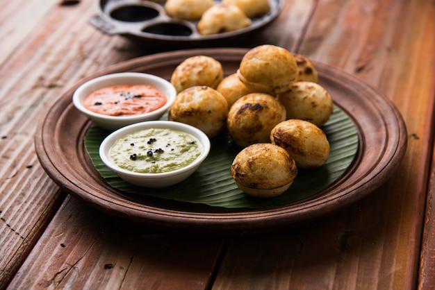 Appam oder Mixed Dal oder Rava Appe serviert auf stimmungsvollem Hintergrund mit grünem und rotem Chutney. Ein beliebtes südindisches Frühstücksrezept in Kugelform. Selektiver Fokus