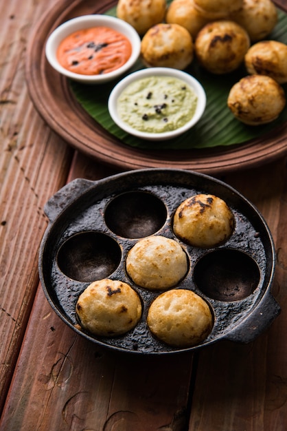 Appam oder Mixed Dal oder Rava Appe serviert auf stimmungsvollem Hintergrund mit grünem und rotem Chutney. Ein beliebtes südindisches Frühstücksrezept in Kugelform. Selektiver Fokus