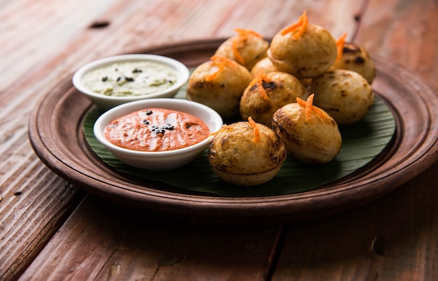 Appam oder Mixed Dal oder Rava Appe serviert auf stimmungsvollem Hintergrund mit grünem und rotem Chutney. Ein beliebtes südindisches Frühstücksrezept in Kugelform. Selektiver Fokus