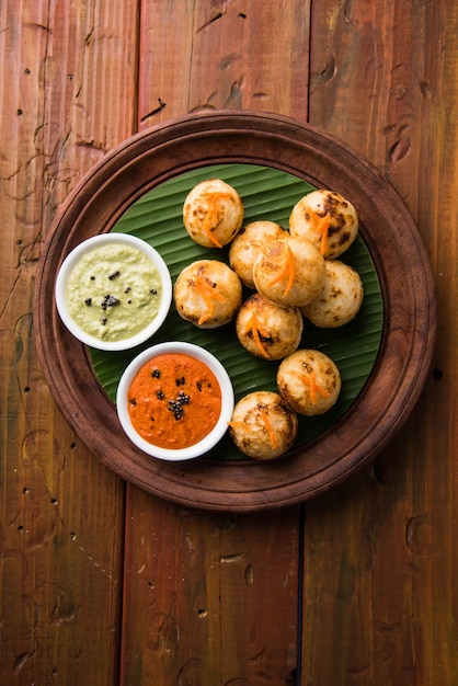 Appam oder Mixed Dal oder Rava Appe serviert auf stimmungsvollem Hintergrund mit grünem und rotem Chutney. Ein beliebtes südindisches Frühstücksrezept in Kugelform. Selektiver Fokus