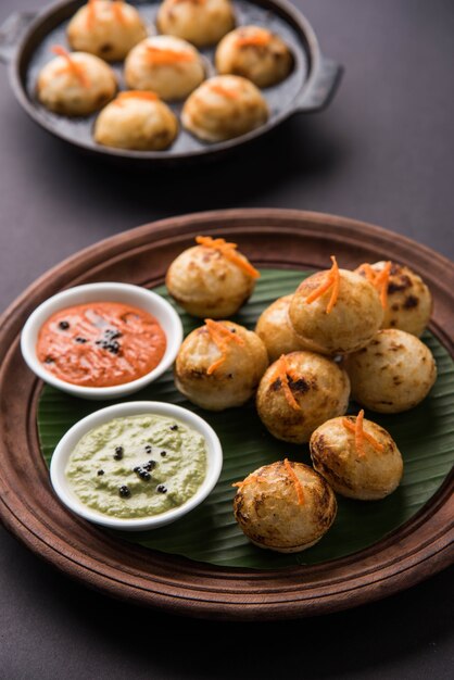 Appam oder Mixed Dal oder Rava Appe serviert auf stimmungsvollem Hintergrund mit grünem und rotem Chutney. Ein beliebtes südindisches Frühstücksrezept in Kugelform. Selektiver Fokus