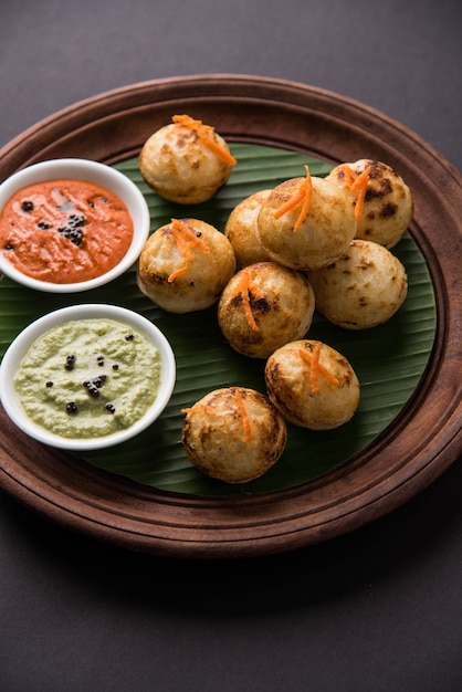 Appam oder Mixed Dal oder Rava Appe serviert auf stimmungsvollem Hintergrund mit grünem und rotem Chutney. Ein beliebtes südindisches Frühstücksrezept in Kugelform. Selektiver Fokus