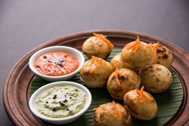 Appam oder Mixed Dal oder Rava Appe serviert auf stimmungsvollem Hintergrund mit grünem und rotem Chutney. Ein beliebtes südindisches Frühstücksrezept in Kugelform. Selektiver Fokus