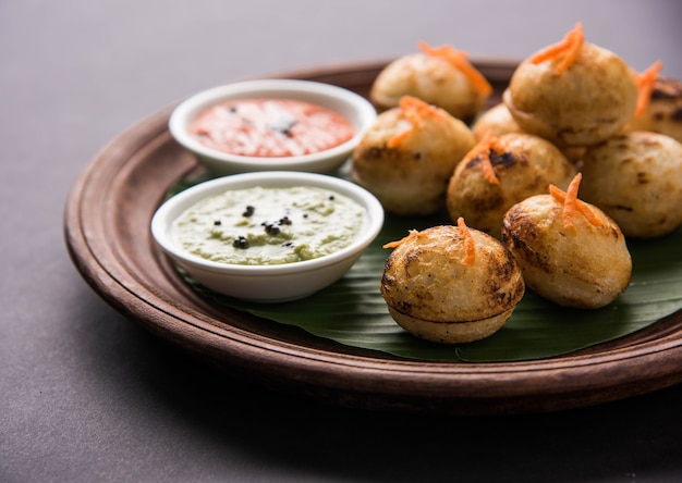 Appam oder Mixed Dal oder Rava Appe serviert auf stimmungsvollem Hintergrund mit grünem und rotem Chutney. Ein beliebtes südindisches Frühstücksrezept in Kugelform. Selektiver Fokus