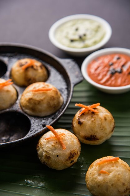 Appam oder Mixed Dal oder Rava Appe serviert auf stimmungsvollem Hintergrund mit grünem und rotem Chutney. Ein beliebtes südindisches Frühstücksrezept in Kugelform. Selektiver Fokus