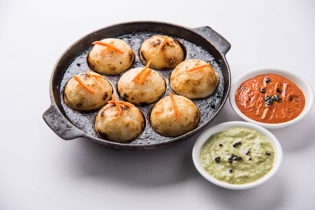 Appam oder Mixed Dal oder Rava Appe serviert auf stimmungsvollem Hintergrund mit grünem und rotem Chutney. Ein beliebtes südindisches Frühstücksrezept in Kugelform. Selektiver Fokus