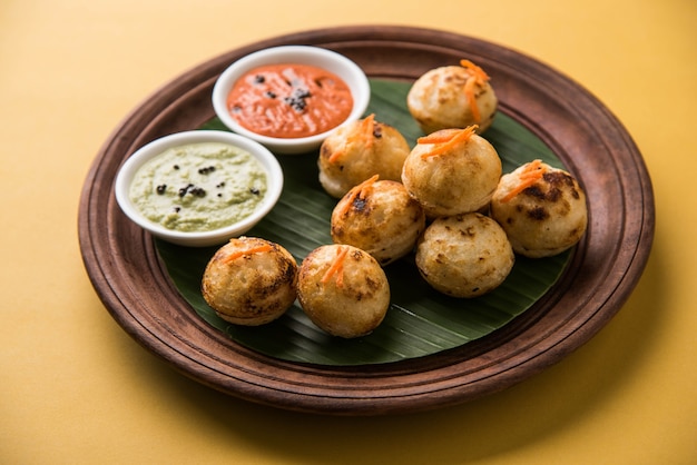 Appam oder Mixed Dal oder Rava Appe serviert auf stimmungsvollem Hintergrund mit grünem und rotem Chutney. Ein beliebtes südindisches Frühstücksrezept in Kugelform. Selektiver Fokus