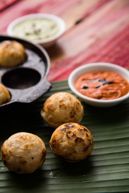 Appam ou Mixed dal ou Rava Appe servido sobre um fundo sombrio com chutney verde e vermelho. Uma receita de café da manhã popular do sul da Índia em forma de bola. Foco seletivo