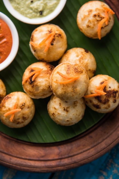 Appam ou Mixed dal ou Rava Appe servido sobre um fundo sombrio com chutney verde e vermelho. Uma receita de café da manhã popular do sul da Índia em forma de bola. Foco seletivo