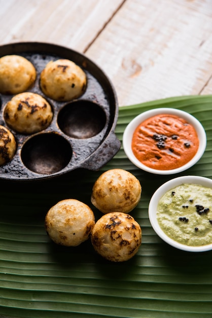 Appam ou Mixed dal ou Rava Appe servido sobre um fundo sombrio com chutney verde e vermelho. Uma receita de café da manhã popular do sul da Índia em forma de bola. Foco seletivo