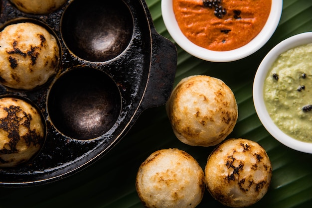 Appam ou Mixed dal ou Rava Appe servido sobre um fundo sombrio com chutney verde e vermelho. Uma receita de café da manhã popular do sul da Índia em forma de bola. Foco seletivo