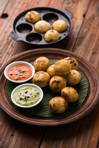 Appam ou Mixed dal ou Rava Appe servido sobre um fundo sombrio com chutney verde e vermelho. Uma receita de café da manhã popular do sul da Índia em forma de bola. Foco seletivo