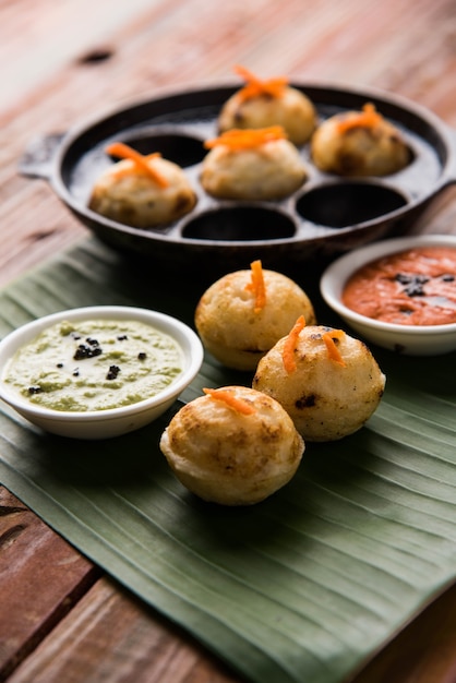 Appam ou Mixed dal ou Rava Appe servido sobre um fundo sombrio com chutney verde e vermelho. Uma receita de café da manhã popular do sul da Índia em forma de bola. Foco seletivo