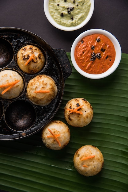 Appam ou Mixed dal ou Rava Appe servido sobre um fundo sombrio com chutney verde e vermelho. Uma receita de café da manhã popular do sul da Índia em forma de bola. Foco seletivo