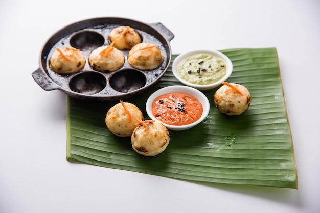 Appam ou Mixed dal ou Rava Appe servido sobre um fundo sombrio com chutney verde e vermelho. Uma receita de café da manhã popular do sul da Índia em forma de bola. Foco seletivo