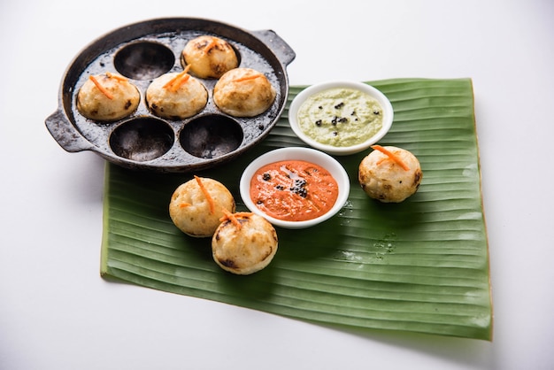 Appam ou Mixed dal ou Rava Appe servido sobre um fundo sombrio com chutney verde e vermelho. Uma receita de café da manhã popular do sul da Índia em forma de bola. Foco seletivo