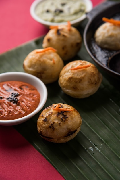 Appam ou Mixed dal ou Rava Appe servido sobre um fundo sombrio com chutney verde e vermelho. Uma receita de café da manhã popular do sul da Índia em forma de bola. Foco seletivo