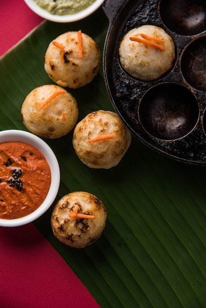 Appam ou Mixed dal ou Rava Appe servido sobre um fundo sombrio com chutney verde e vermelho. Uma receita de café da manhã popular do sul da Índia em forma de bola. Foco seletivo