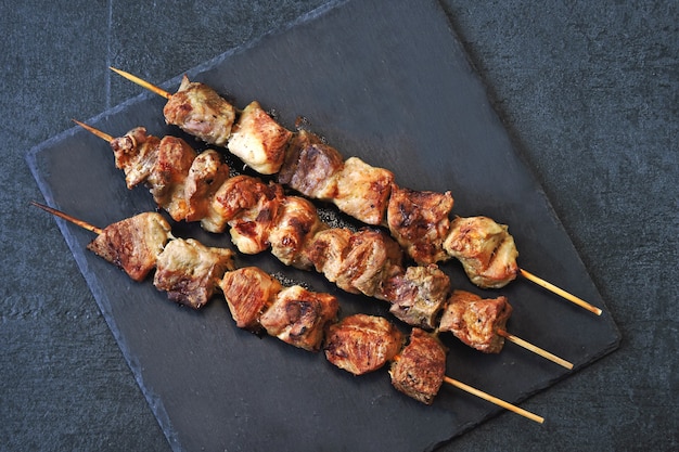 Appetitanregende rötliche kebabs auf einer dunklen steinoberfläche. ansicht von oben.