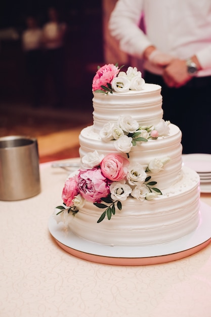 Appetitanregender frischer Gebäckkuchen bedeckt durch weiße Sahneglasur und verzieren die süße Blumenumhüllung auf Tabelle