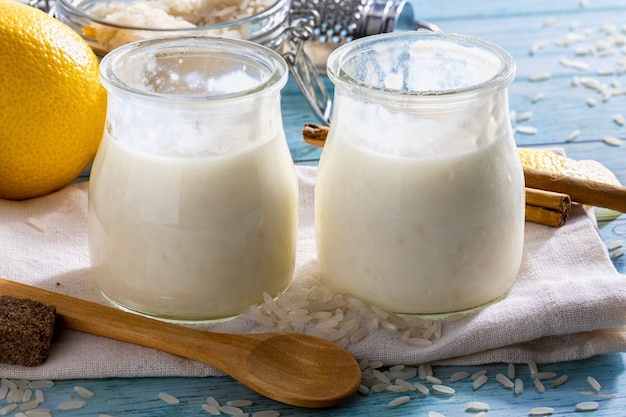 Appetitanregender Milchreis im Glas mit Zimtstangen, Reiskörnern, Milch und Zitronen