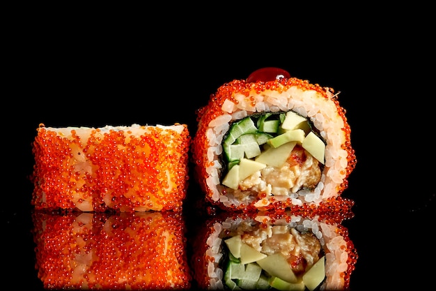 Appetitanregendes kalifornisches Sushi in Tobiko-Kaviar mit Aal und Avocado auf dunklem Hintergrund. Nahaufnahme, selektiver Fokus