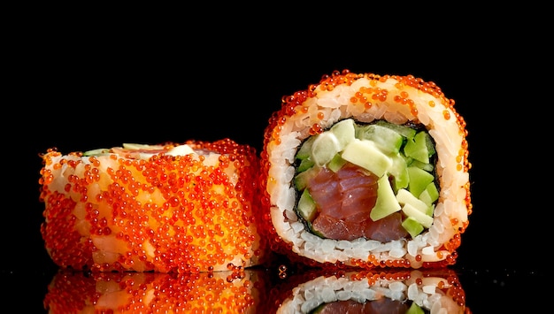 Appetitanregendes kalifornisches Sushi in Tobiko-Kaviar mit Thunfisch und Avocado auf dunklem Hintergrund. Nahaufnahme, selektiver Fokus