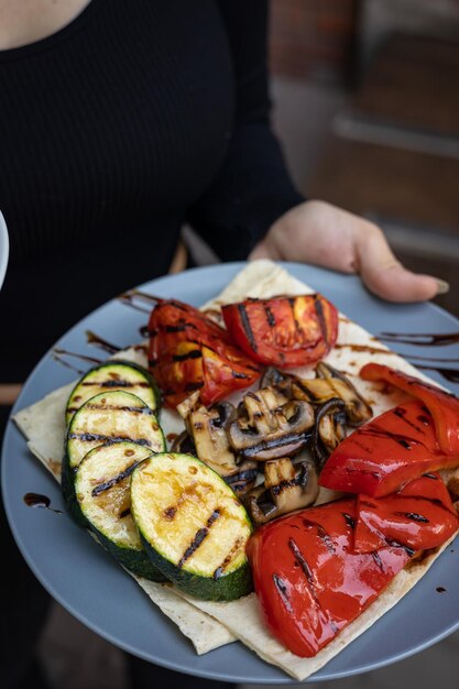 Appetitlich gegrilltes Gemüse auf Tellern auf einem dunklen Holztisch